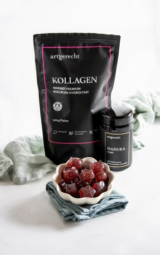 Fruchtige Kollagen Gummies in Herz- und Würfelformen auf einem Teller, mit frischen Beeren und Minze garniert