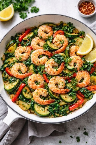 Pfanne mit gebratenen Garnelen, Zucchini, Paprika und Blattgem&uuml;se, frisch angerichtet.